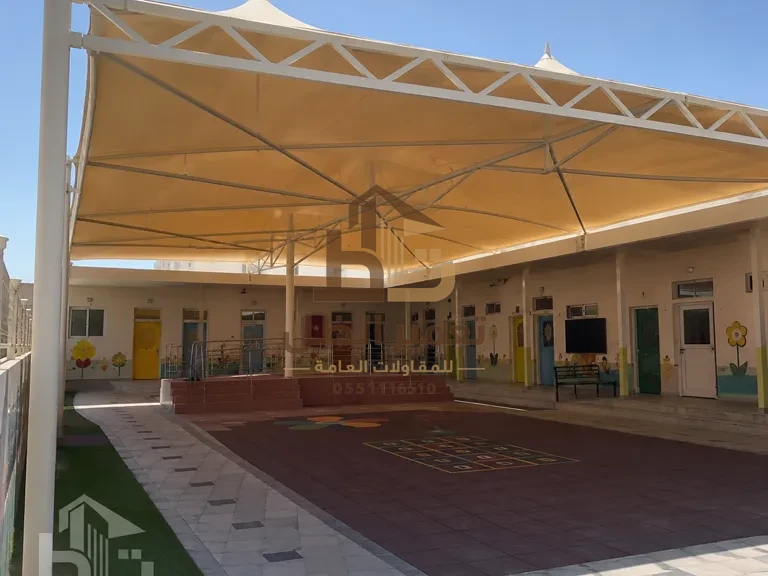 مظلة تظليل تغطّي مدخل مدرسة وجزءًا من الفناء الخارجي