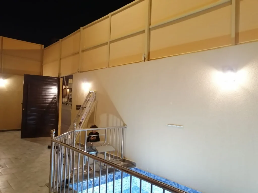 ساتر ألواح حول فناء مسبح مع سلّم عمل أثناء التنفيذ