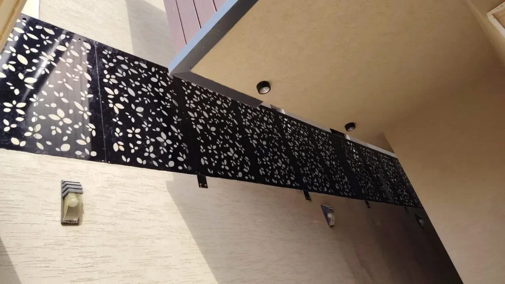 ساتر ليزر أسود بنقش أوراق مفرّغة مثبّت أعلى جدار فيلا