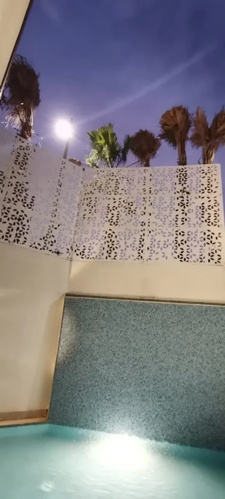 سواتر ليزر بيضاء بنقش زخرفي حول مسبح منزلي ليلاً