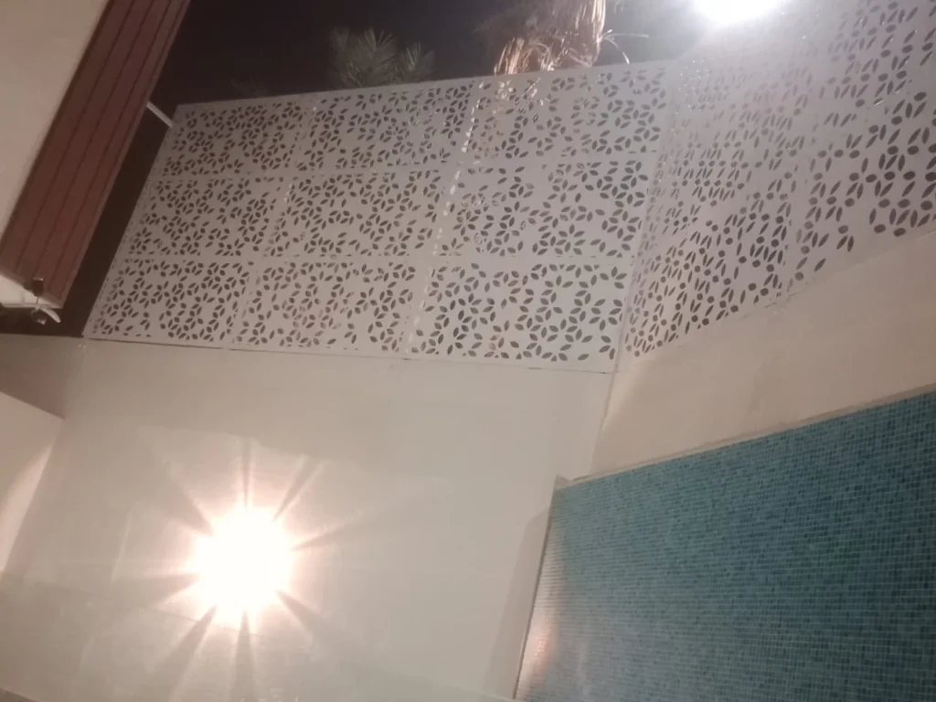 ألواح ساتر ليزر بيضاء بنقوش هندسية تحيط بمسبح داخلي