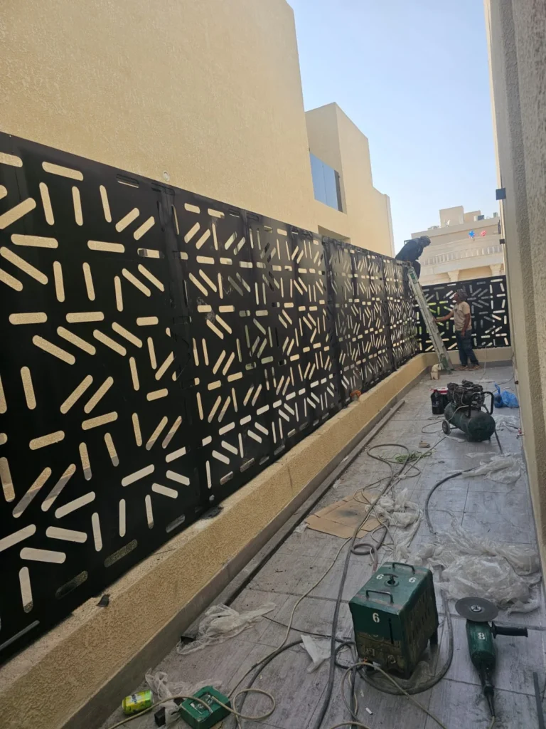 عمّال يركّبون ألواح ساتر ليزر سوداء على سطح مبنى أثناء التنفيذ