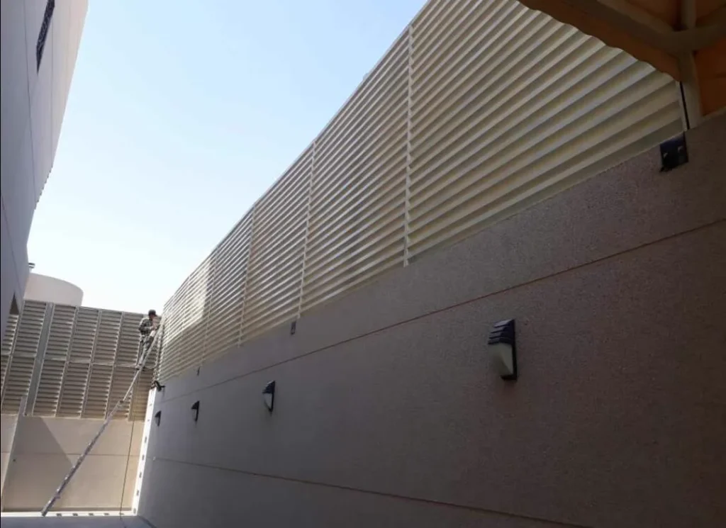 ساتر شرائح معدنية أفقية فاتحة على طول سور خارجي في جدة