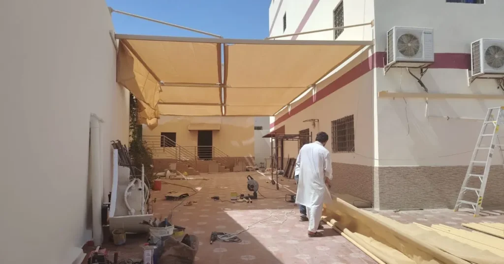 موقع عمل أثناء تركيب مظلة فناء مع شرائح وقوائم مجهّزة على الأرض