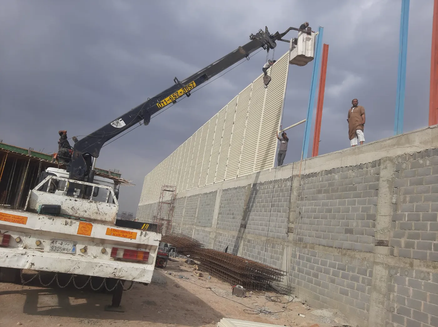رافعة ومعدات أثناء تركيب ساتر معدني على جدار في جدة