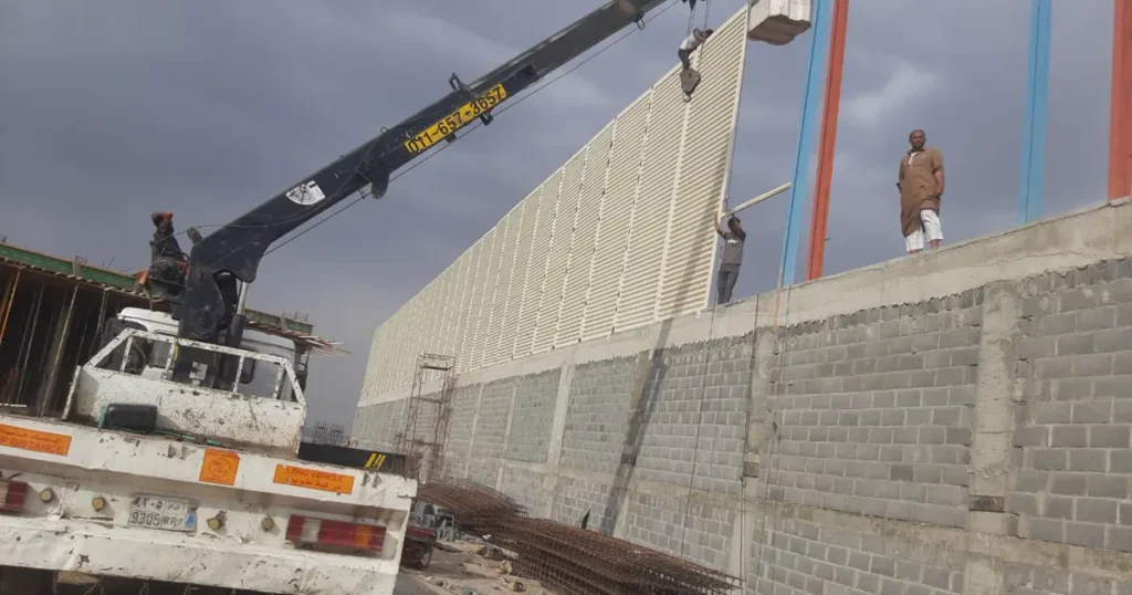 رافعة ترفع المواد أثناء تركيب ساتر معدني على جدار في جدة