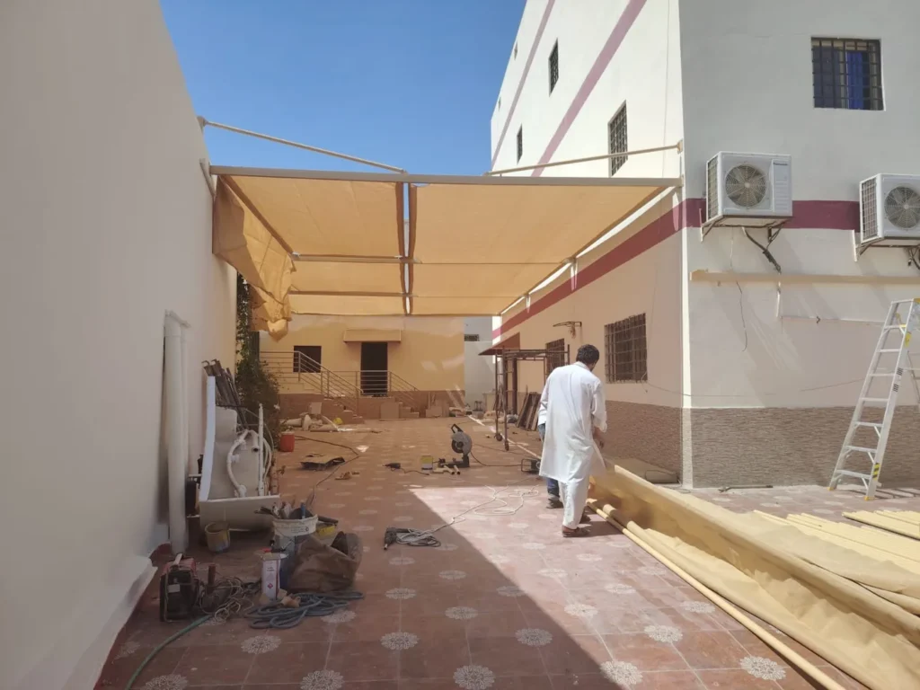 موقع عمل أثناء تركيب مظلة فناء مع شرائح وقوائم مجهّزة على الأرض