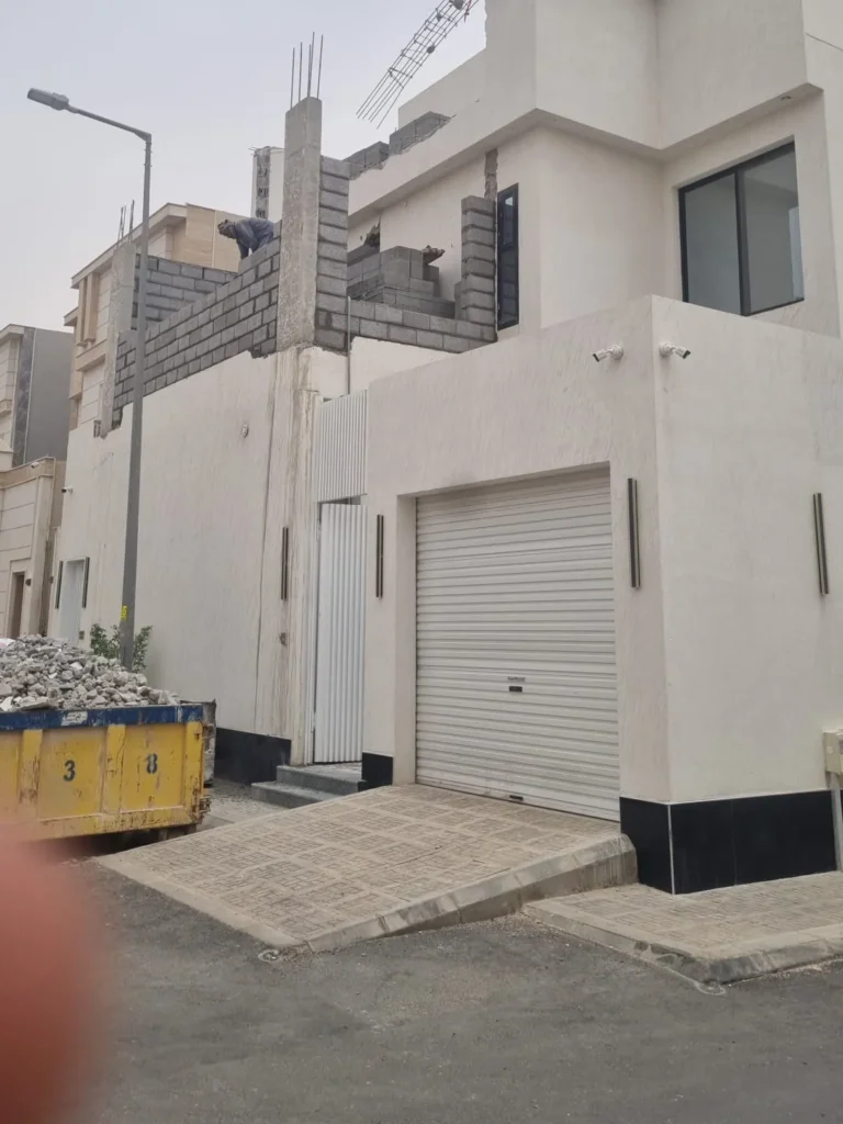 واجهة فيلا بباب كراج مع أعمال بناء بالبلوك في الدور العلوي