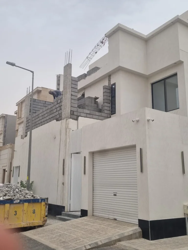 واجهة فيلا بباب كراج مع أعمال بناء بالبلوك في الدور العلوي من زاوية مقاربة
