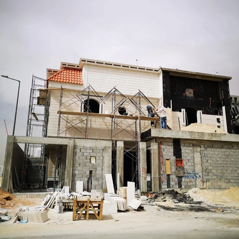 فيلا قيد الإنشاء بجدران بلوك وسقالات ومواد بناء أمامها