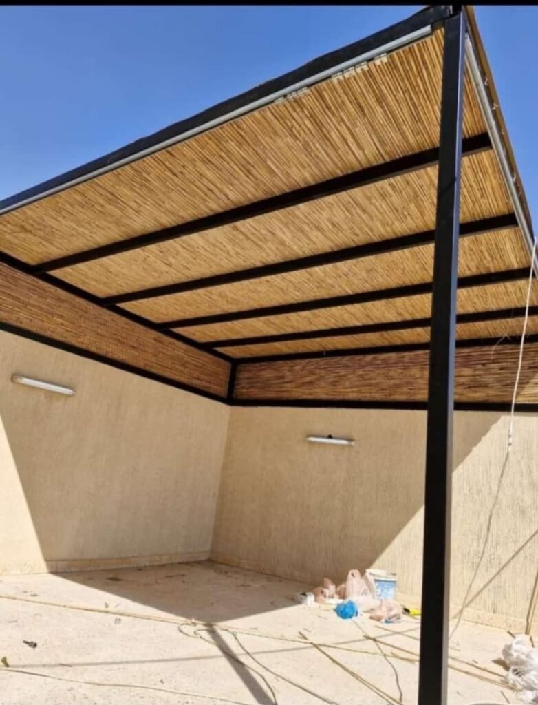 برجولا بسقف من عيدان البامبو على هيكل معدني أسود فوق فناء