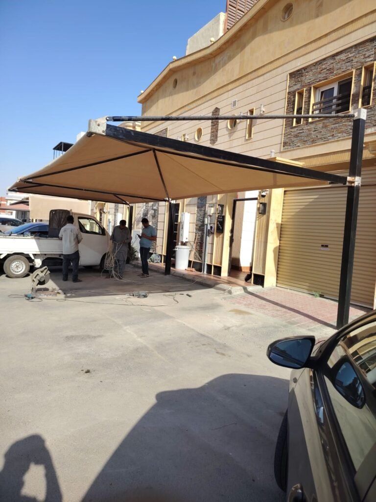 مظلة بتغطية فاتحة فوق فناء وأمامها فريق عمل وسيارة نقل