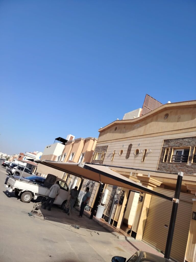 صف من مظلات المواقف بتغطية فاتحة أمام منازل في شارع سكني
