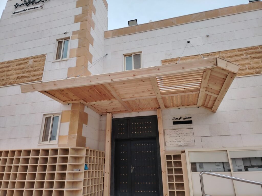 لقطة قريبة لمظلة مدخل بشرائح خشبية المظهر فوق باب مبنى وخزائن جانبية