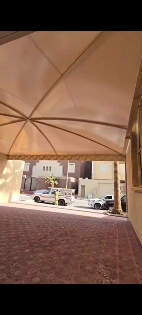 منظر من أسفل مظلة قماشية تغطي ممر سيارات ويظهر الشارع في نهايته